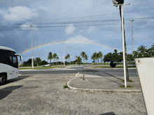 a bus is parked in front of a rainbow and palm trees