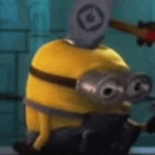 a close up of a yellow minion with a hammer on his head .