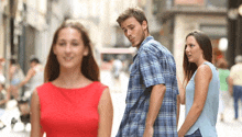 a man and a woman are walking down a street and the woman is looking at the man 's back .