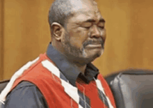 a man in a red vest is crying in a courtroom .