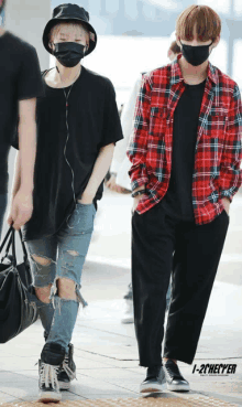 a man wearing a black shirt and a red plaid shirt is walking next to another man