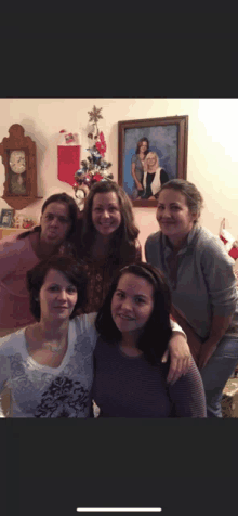 a group of women posing for a picture in front of a clock and a christmas tree