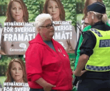 a woman in a red jacket is standing in front of a poster that says " medmannenslighet for sverige framat "