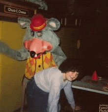 a chuck e cheese mascot stands next to a woman