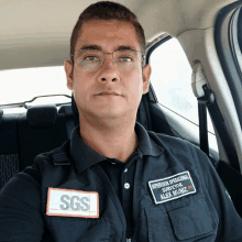 a man wearing glasses and a sgs patch on his vest