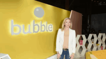 a woman stands in front of a yellow wall with the word bubble on it