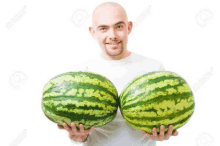 a bald man is holding two watermelons in his hands and smiling .