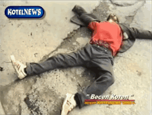 a man in a red shirt is laying on the ground in front of a kotelnews sign