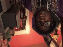 a person wearing glasses and a purple hoodie is laying down