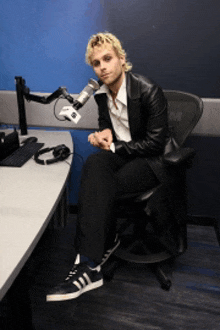 a man in a leather jacket sits in front of a microphone with the letters wm on it