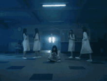 a group of women in white coats are standing around a girl sitting on the floor in a dark room