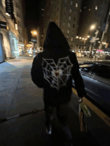 a person wearing a black hoodie with a spider web design on the back