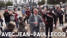 a man in a suit is dancing in front of a crowd with the words avec jean-paul lecoq on the bottom