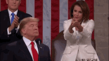 a man in a suit and tie is sitting next to a woman in a white suit and tie .