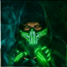 a man wearing a mask and gloves with green lights on them is standing in the dark .