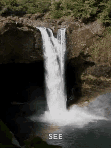 a waterfall in the middle of a forest with the words `` see '' written on the bottom of the waterfall .