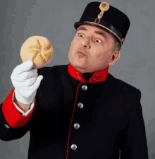 a man in a military uniform is holding a roll of bread in his hand