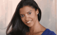 a woman wearing a blue shirt and earrings smiles at the camera