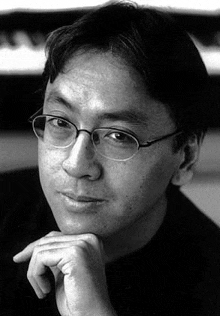 a man wearing glasses and a black shirt is sitting in front of a piano .