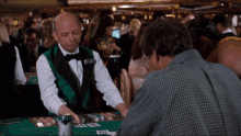 a man playing a game of blackjack in a casino with a man wearing a name tag that says james bond