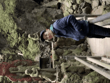 a man in a blue jacket stands in front of a statue that says ' a ' on it