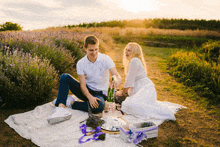 a man and woman are sitting on a blanket in a lavender field