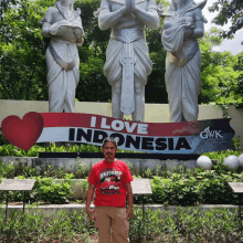 a man stands in front of a sign that says " i love indonesia "