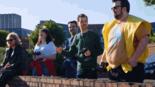 a group of people are standing on a brick wall and one of them is wearing a yellow vest with a cat on it