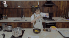 a woman in a white apron is pouring liquid into a pan in a kitchen with a sign that says twice