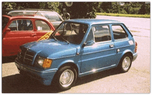 a blue car is parked next to a red car with a yellow tape on the windshield