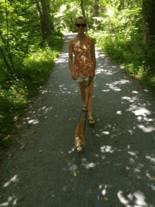 a woman is walking a dog on a leash on a path