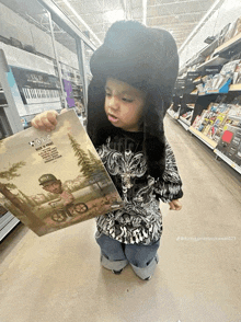 a little boy wearing a furry hat is holding a cd that says ' ice cube ' on it