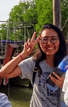 a woman wearing a shirt that says " a way to remember " is giving the peace sign