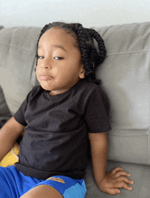 a little boy with braids sits on a couch with his eyes closed