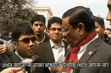 a man in a suit and scarf is talking to another man in a crowd with a caption in another language