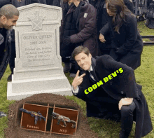 a man kneeling in front of a grave that says oliver queen on it