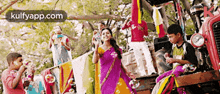 a woman in a purple sari is blowing soap bubbles in front of a group of children sitting on a tractor .