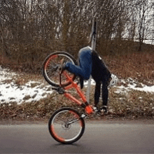 a man is doing a trick on a bicycle on the side of the road .