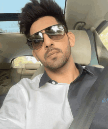 a man wearing sunglasses sits in a car