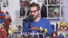 a man wearing glasses and a blue shirt stands in front of a microphone with the words " not happening " below him