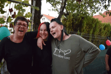 three women are posing for a picture and one has a shirt that says faith hope love