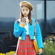 a woman wearing a plaid skirt and a beret looks at her phone