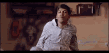 a man in a striped shirt is making a funny face while dancing in a room .