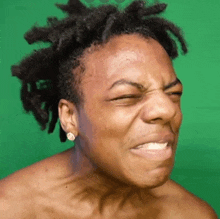 a shirtless man with dreadlocks is making a funny face .