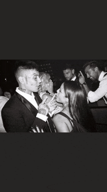 a man with a tattoo on his face talks to a woman in a black and white photo