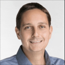 a man is wearing a blue shirt and smiling for the camera .