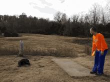 a man throwing a frisbee in a field while wearing an orange shirt that says ' georgia ' on it