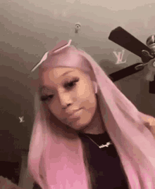 a girl with long pink hair is standing in front of a ceiling fan in a room .