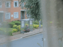 a woman sits at a bus stop in front of a building with a sign that says ' no parking '