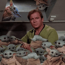 a man is holding a bunch of baby yoda dolls in his arms .